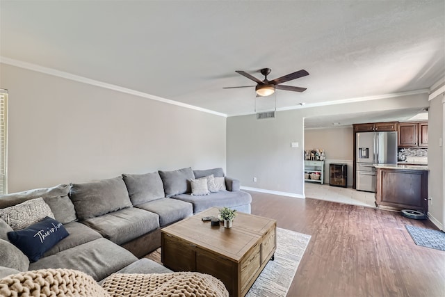 living room with light hardwood / wood-style floors, beverage cooler, ornamental molding, and ceiling fan