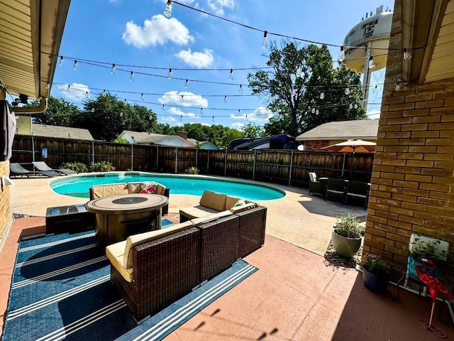 view of swimming pool featuring a patio area and an outdoor living space with a fire pit