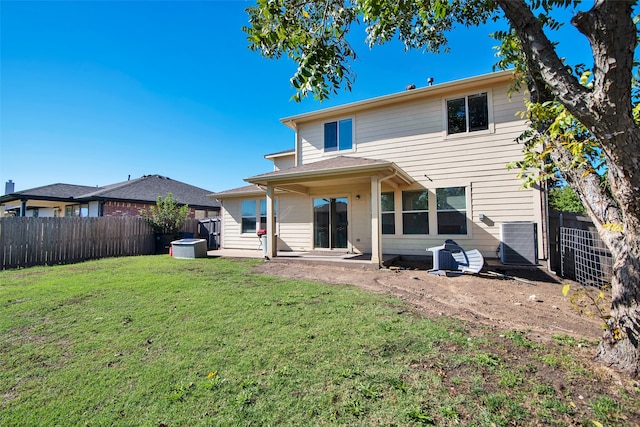 rear view of house with central AC unit and a lawn