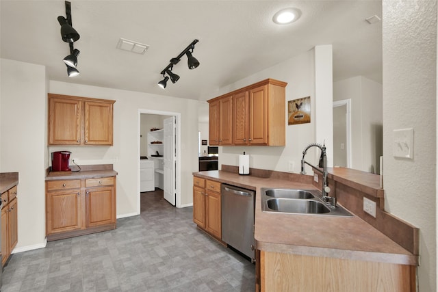 kitchen with dishwasher, track lighting, washer / clothes dryer, and sink