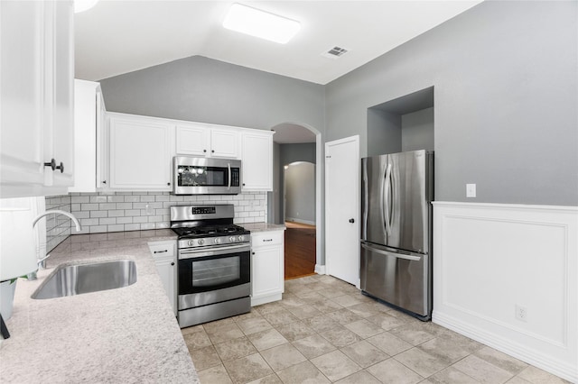 kitchen with white cabinets, lofted ceiling, stainless steel appliances, tasteful backsplash, and sink