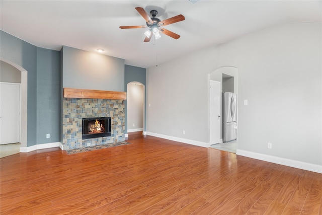 unfurnished living room featuring a tile fireplace, light hardwood / wood-style flooring, and ceiling fan