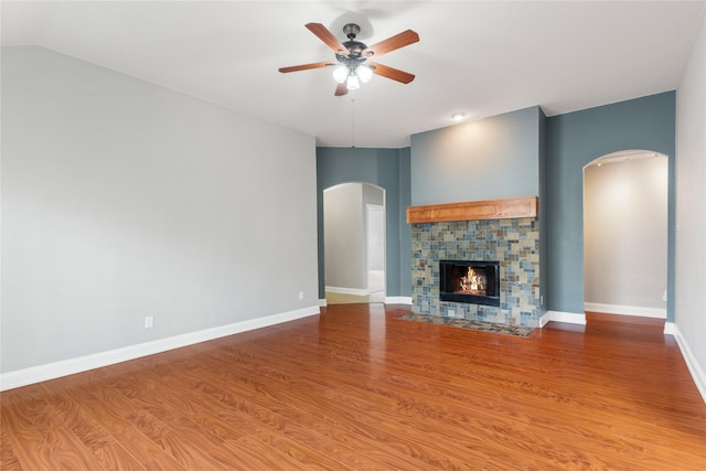 unfurnished living room featuring ceiling fan, hardwood / wood-style flooring, and a stone fireplace