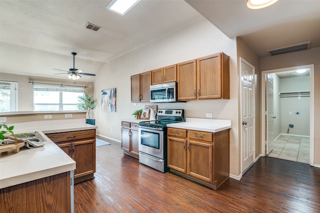 kitchen with appliances with stainless steel finishes, lofted ceiling, ceiling fan, and dark hardwood / wood-style flooring