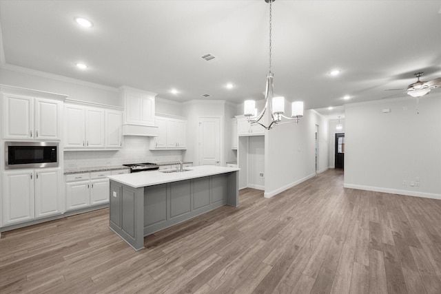 kitchen with a center island with sink, light hardwood / wood-style floors, white cabinetry, and stainless steel appliances