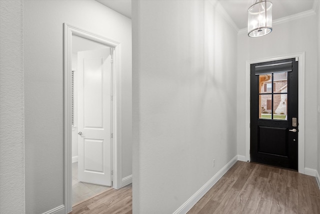 foyer with a chandelier, light hardwood / wood-style flooring, and crown molding