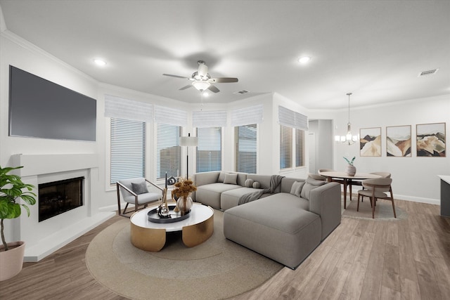 living room with hardwood / wood-style floors, ceiling fan with notable chandelier, and ornamental molding