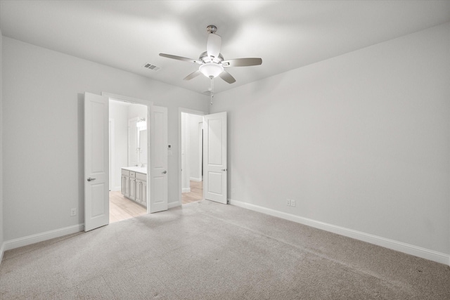 unfurnished bedroom with ceiling fan, light colored carpet, and ensuite bathroom