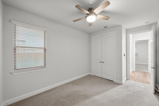 unfurnished bedroom featuring ceiling fan, light colored carpet, and a closet