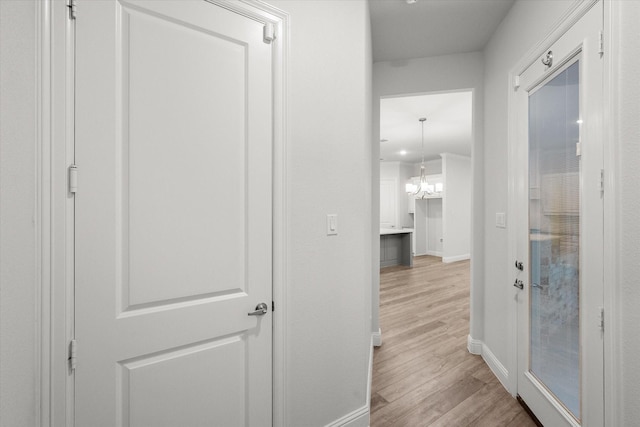 hallway with a chandelier and light hardwood / wood-style flooring