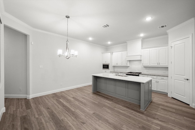 kitchen featuring white cabinetry, sink, stainless steel appliances, a kitchen island with sink, and hardwood / wood-style flooring