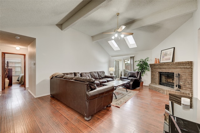 living room with dark hardwood / wood-style floors, lofted ceiling with skylight, a textured ceiling, and a brick fireplace