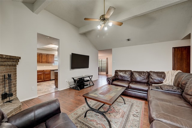 living room featuring vaulted ceiling with beams, ceiling fan, light wood-type flooring, and a textured ceiling