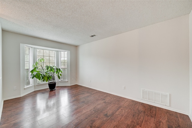 unfurnished room featuring dark wood-type flooring and a textured ceiling