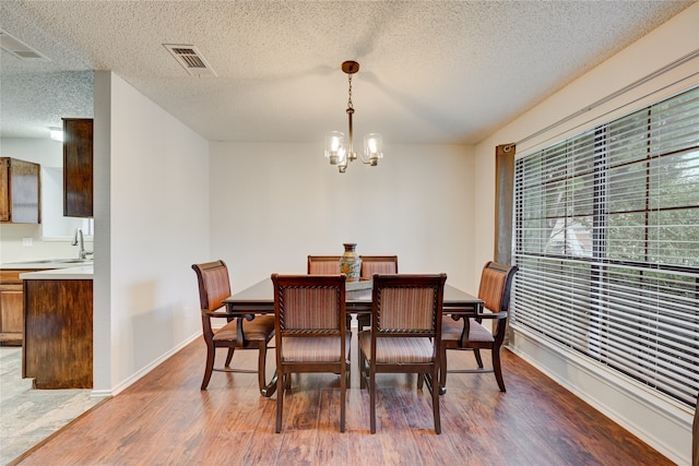 dining room with hardwood / wood-style floors, a chandelier, a textured ceiling, and sink