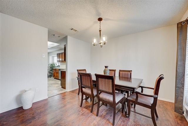 dining room with a notable chandelier, a textured ceiling, and light wood-type flooring