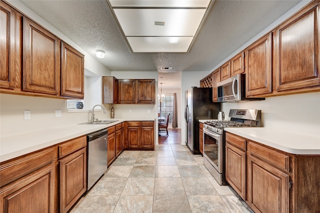 kitchen featuring sink, a textured ceiling, appliances with stainless steel finishes, and a chandelier