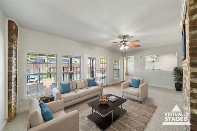 carpeted living room featuring french doors, sink, and ceiling fan