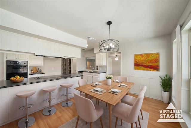 dining area featuring a chandelier, sink, and light hardwood / wood-style floors