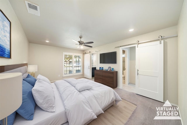 carpeted bedroom featuring a barn door and ceiling fan