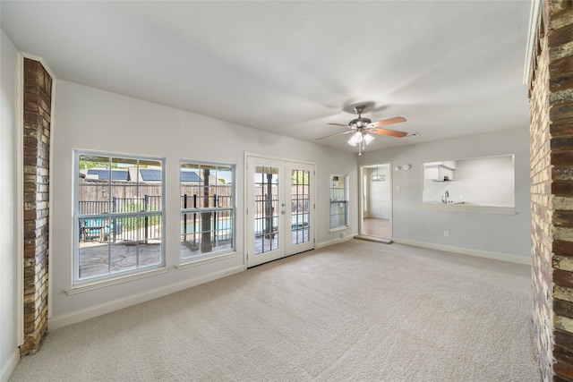 unfurnished living room with french doors, ceiling fan, and light colored carpet