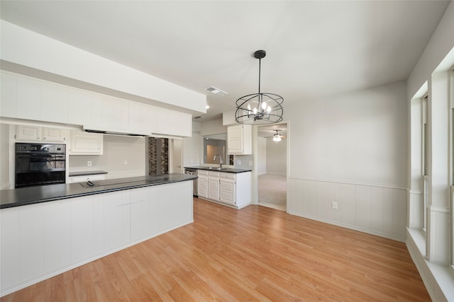 kitchen with oven, hanging light fixtures, white cabinetry, light hardwood / wood-style floors, and sink