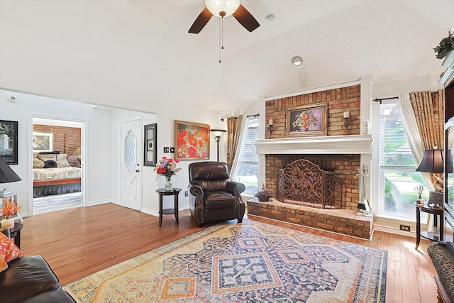 living room with a fireplace, a wealth of natural light, wood-type flooring, and ceiling fan