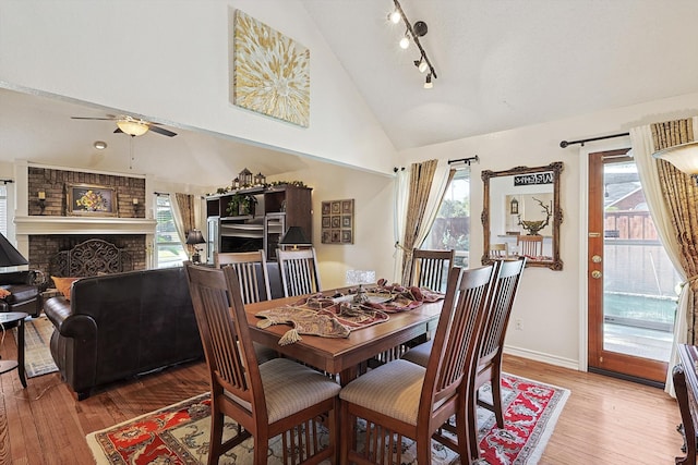 dining space with hardwood / wood-style floors, a wealth of natural light, vaulted ceiling, and a brick fireplace