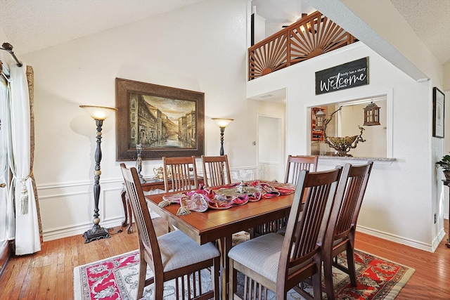 dining space with high vaulted ceiling and hardwood / wood-style flooring