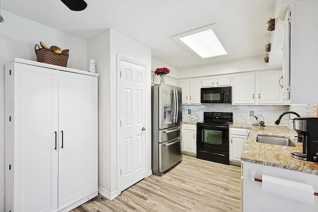 kitchen featuring light hardwood / wood-style floors, sink, black appliances, light stone countertops, and white cabinets