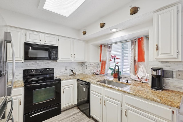 kitchen with light hardwood / wood-style floors, white cabinets, black appliances, sink, and backsplash