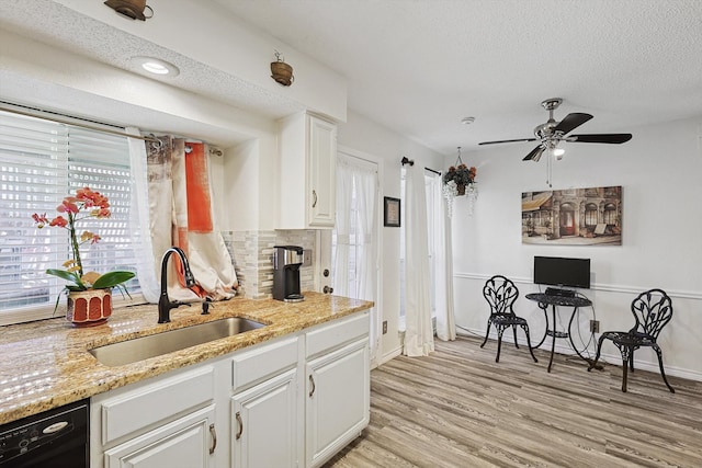 kitchen featuring a textured ceiling, white cabinetry, sink, and light wood-type flooring