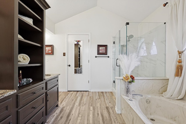 bathroom with hardwood / wood-style floors, vanity, separate shower and tub, and lofted ceiling