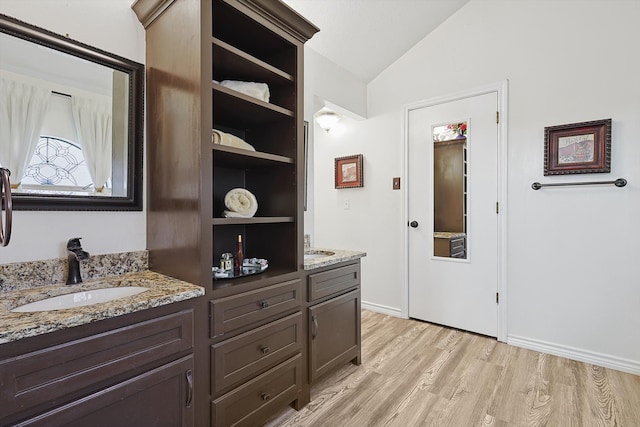 bathroom featuring hardwood / wood-style flooring, vanity, and vaulted ceiling