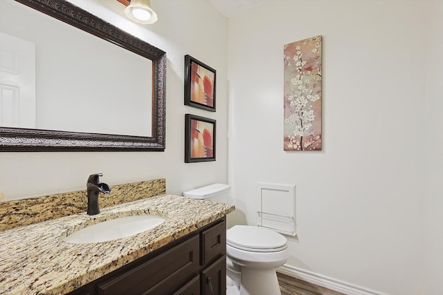 bathroom with wood-type flooring, toilet, and vanity