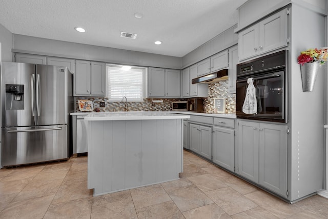 kitchen with tasteful backsplash, a kitchen island, appliances with stainless steel finishes, a textured ceiling, and gray cabinetry