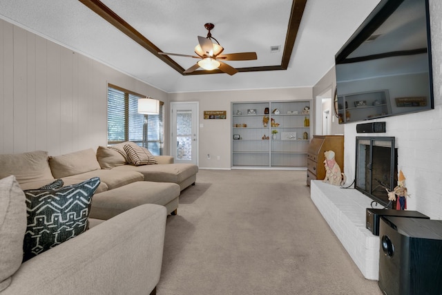 carpeted living room with a brick fireplace, a textured ceiling, wooden walls, and ceiling fan