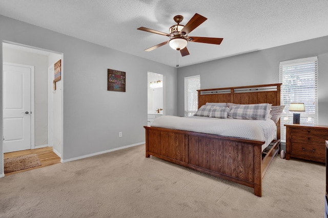 carpeted bedroom with a textured ceiling, ensuite bath, and ceiling fan