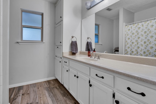 bathroom with toilet, hardwood / wood-style floors, curtained shower, vanity, and a textured ceiling