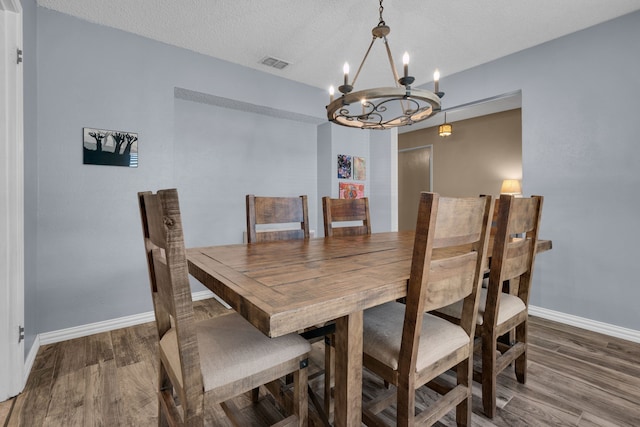 dining space featuring a textured ceiling, a chandelier, and wood-type flooring