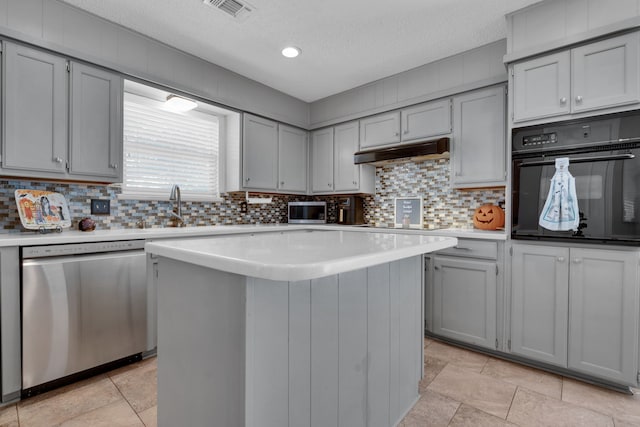 kitchen with gray cabinetry, appliances with stainless steel finishes, a textured ceiling, a center island, and decorative backsplash