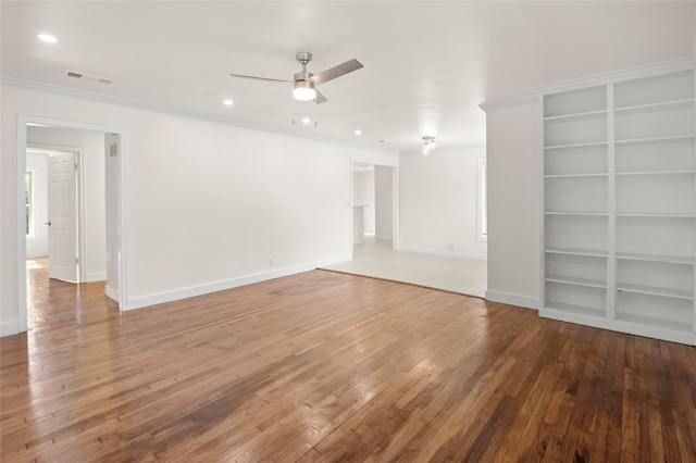 unfurnished room featuring built in shelves, ceiling fan, ornamental molding, and hardwood / wood-style flooring