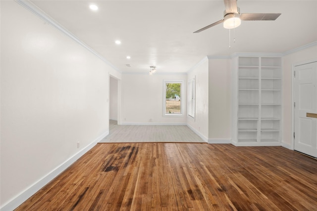 unfurnished living room featuring built in features, hardwood / wood-style flooring, ceiling fan, and ornamental molding