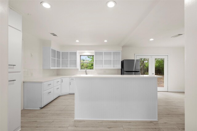 kitchen with white cabinetry, sink, stainless steel refrigerator, and light hardwood / wood-style flooring