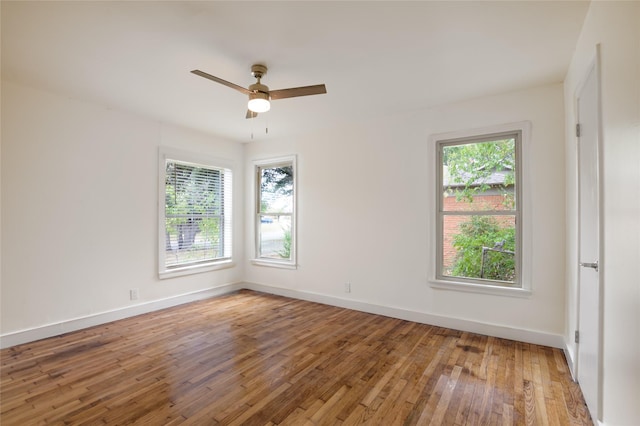 empty room featuring ceiling fan, a healthy amount of sunlight, and wood-type flooring