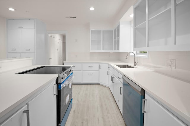 kitchen featuring light hardwood / wood-style flooring, appliances with stainless steel finishes, sink, white cabinetry, and decorative backsplash