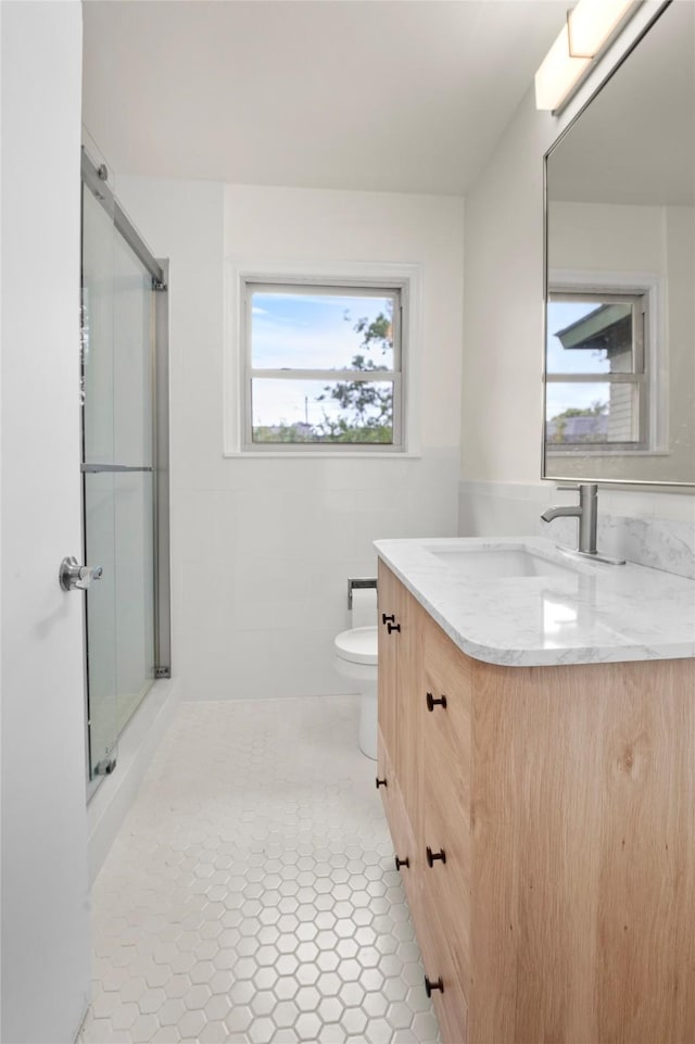 bathroom with vanity, toilet, an enclosed shower, and tile patterned flooring