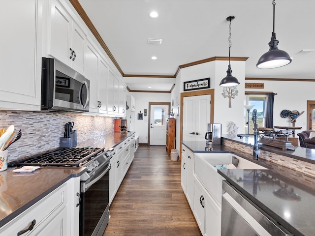 kitchen featuring dark wood-type flooring, stainless steel appliances, ornamental molding, decorative light fixtures, and white cabinets