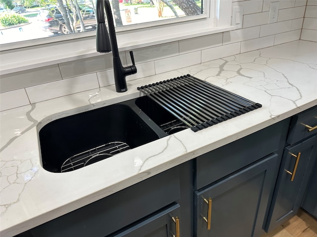 interior details with backsplash, light stone countertops, and sink