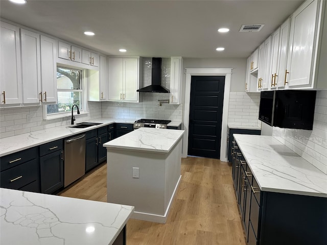 kitchen featuring stainless steel appliances, white cabinetry, a kitchen island, and wall chimney range hood